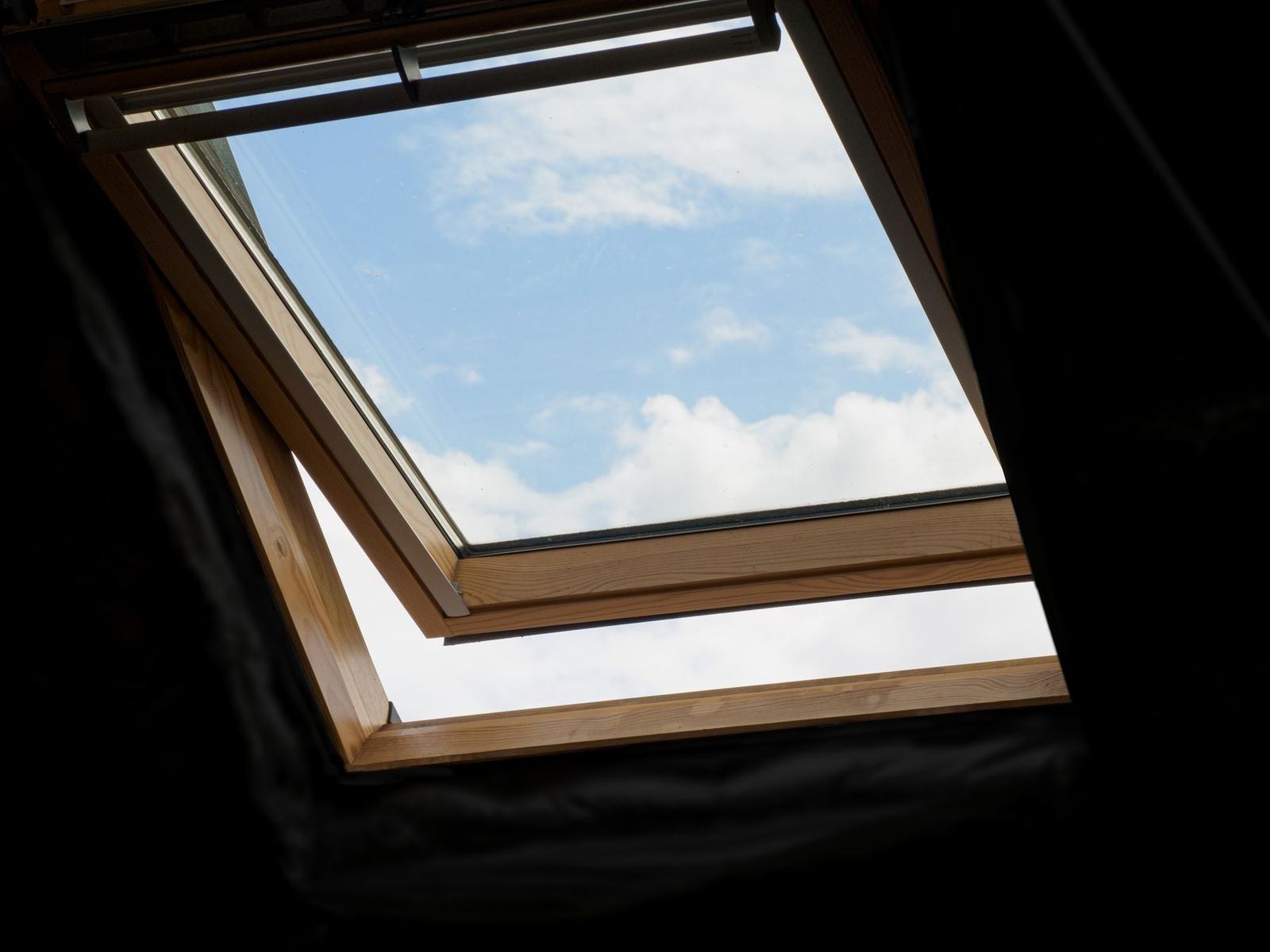 Fenêtre de toit ouverte dans des combles, vue sur le ciel